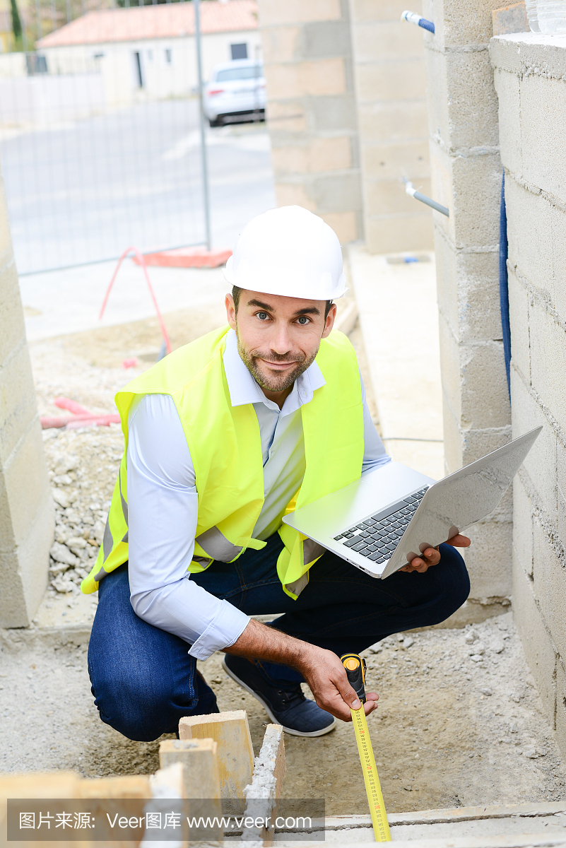 英俊的年輕人工頭建筑師監督一個新房子建筑工地