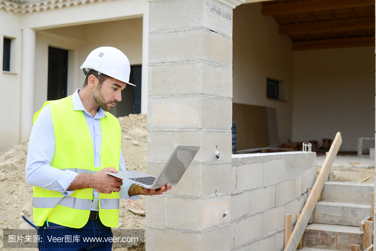 英俊的年輕人工頭建筑師監督一個新房子建筑工地